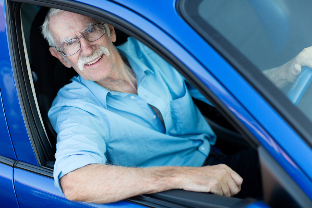 Happy elder man driving a blue car